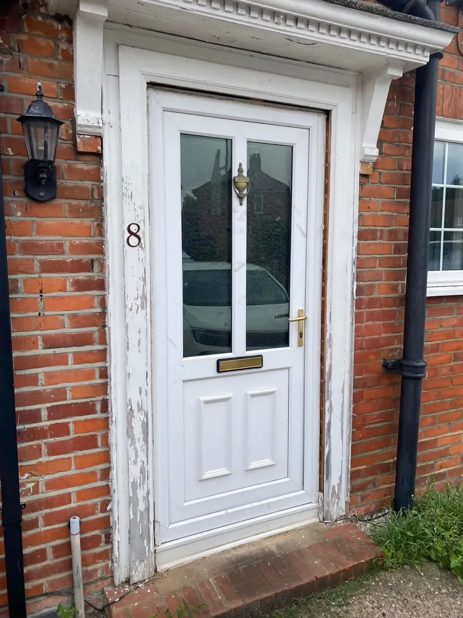 Before: a white uPVC front door with a worn, peeling timber surround